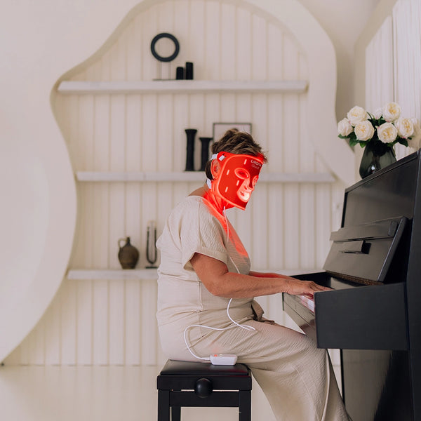 Mujer toca el piano mientras lleva puesta la máscara LED facial GLOW de Liroma