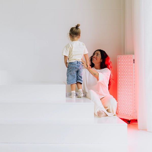 Mujer con un niño junto al panel de luz roja Liroma Elite en el salón
